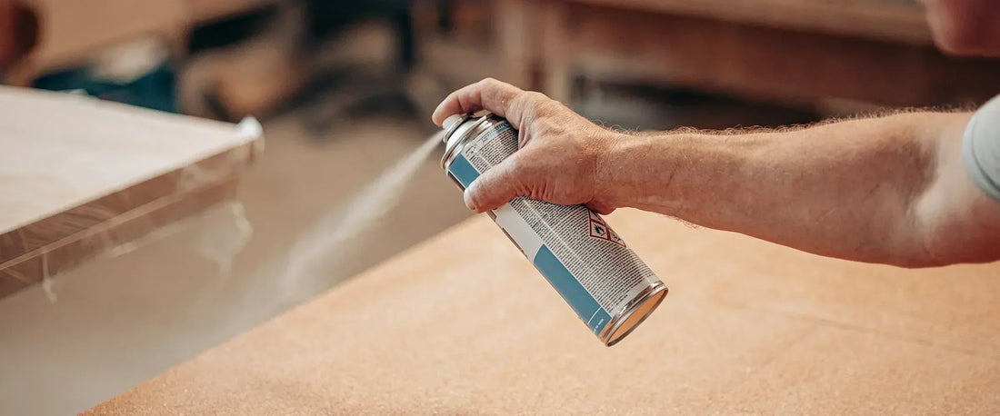 Person using a spray can on a surface with a blurred background