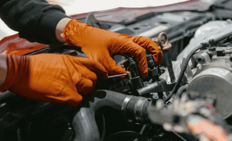 Person wearing orange gloves working on a car engine